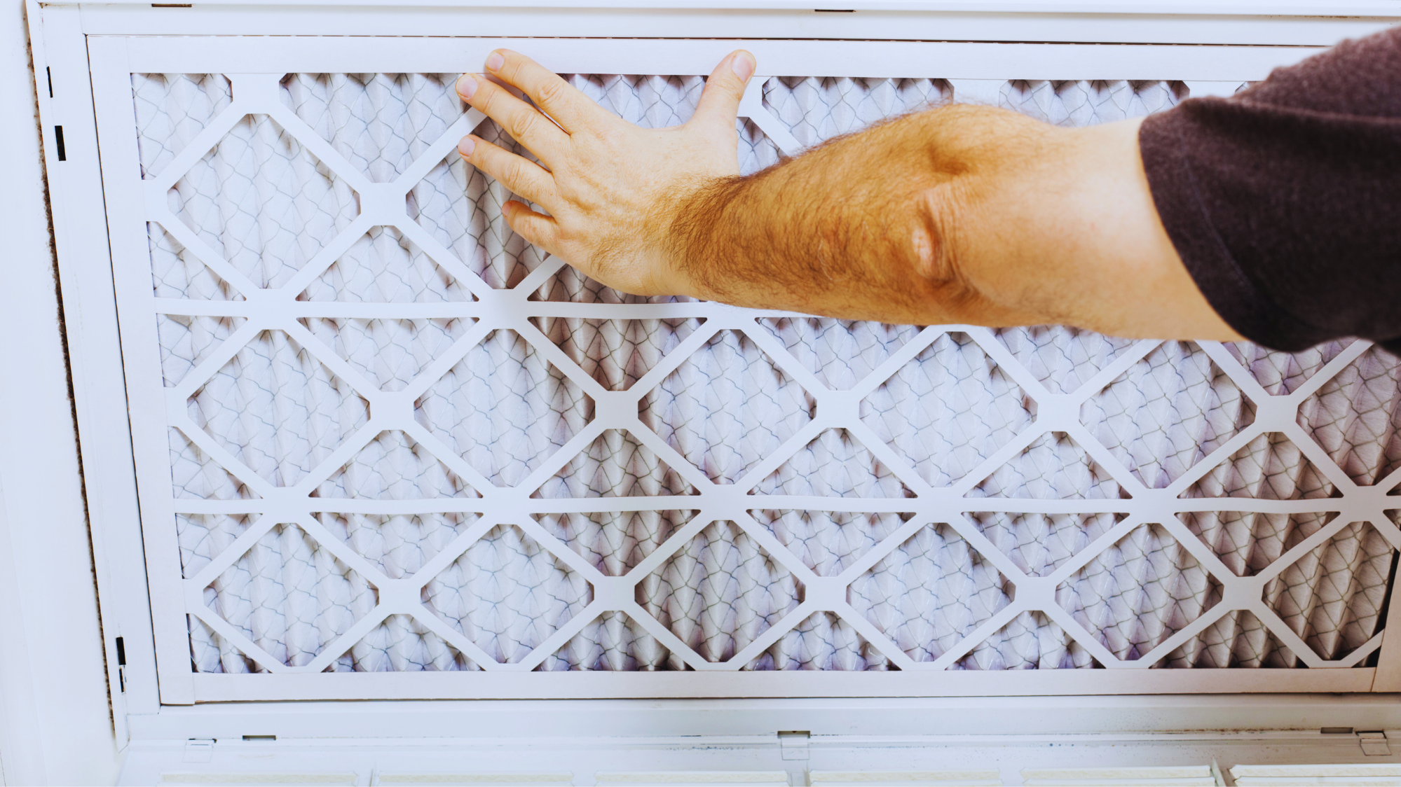 Close-up of a clean AC filter being replaced by a homeowner in a modern home.